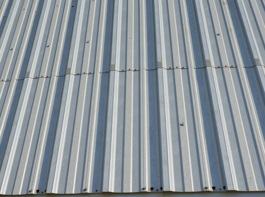Corrugated metal roofing panels with exposed fasteners